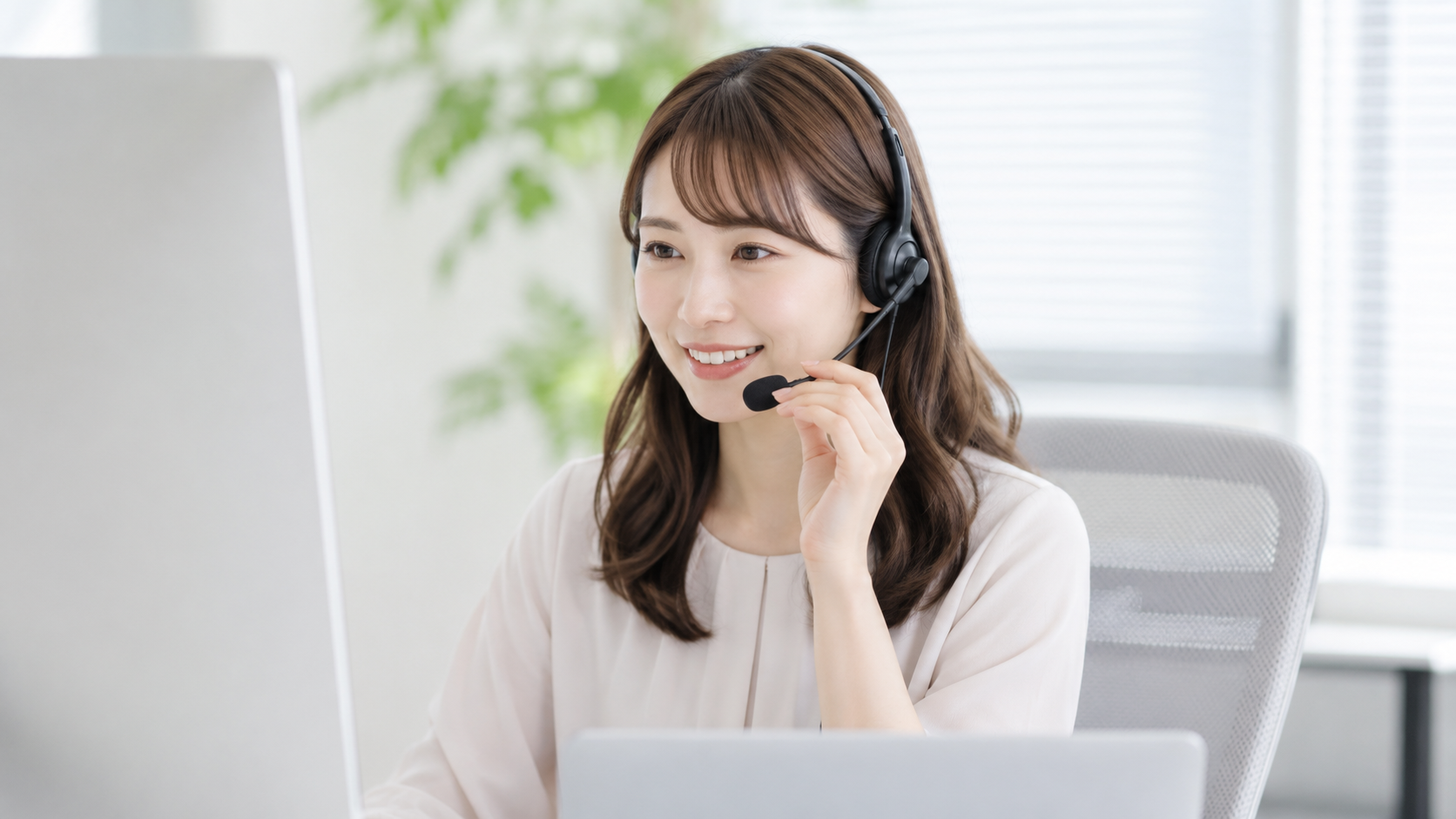 ヘッドセットをつけてパソコンで対応する女性